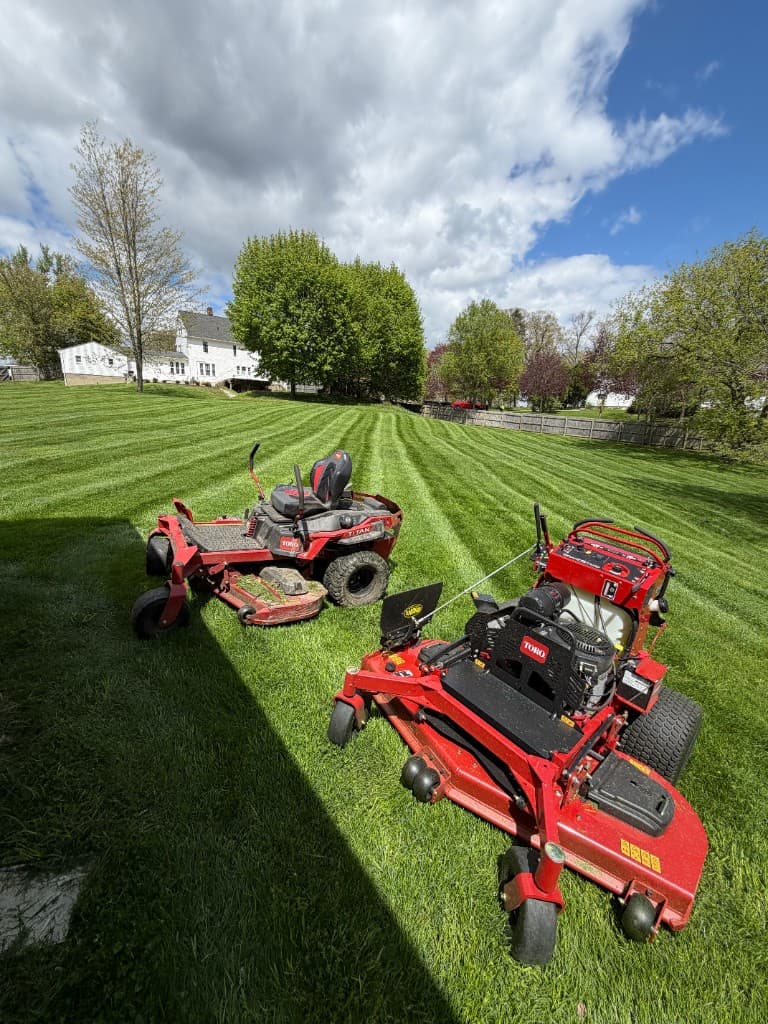 Zero-turn mowers on professionally striped residential lawn Grand Rapids Michigan